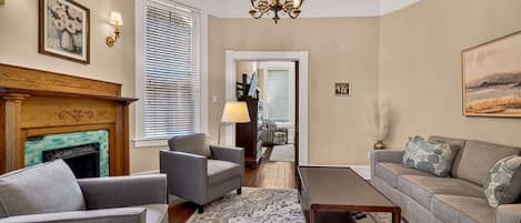 A living room with a fireplace, two armchairs, a sofa, a coffee table, and a chandelier.