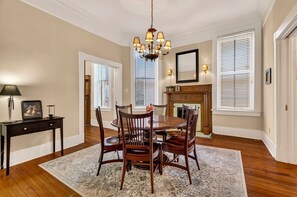 Une salle à manger avec une table ronde, des chaises en bois, un lustre et une cheminée.