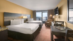Ein Hotelzimmer mit zwei Betten, einem Schreibtisch, einem Stuhl, einem Fernseher und einem Balkon mit Aussicht.