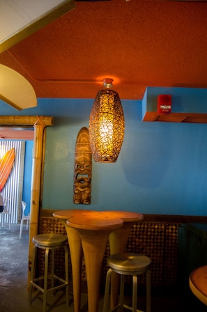 A bar area with a wooden table and stools, a decorative wall hanging, and a hanging light fixture. - Beautiful Oceanfront Guest Room + Official On-Site Rental Privileges (Myrtle Beach)
