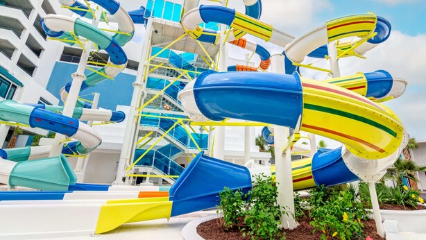 A water park with multiple slides and a pool area, surrounded by a white building with balconies. - Beautiful Oceanfront Guest Room + Official On-Site Rental Privileges (Myrtle Beach)