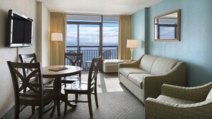 A hotel room with a dining area, a sofa, a TV, and a balcony with a view. - Oceanfront Suite w/ Private Balcony + Official On-Site Rental Privileges (Myrtle Beach)