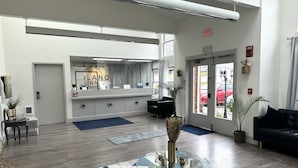 A hotel lobby with a reception desk, a black sofa, and a glass coffee table.