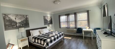 Ein Hotelzimmer mit Bett, Schreibtisch, Sessel und Fernseher.