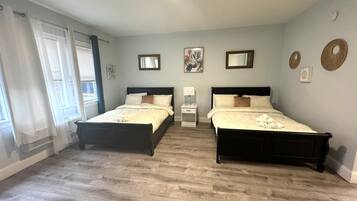 A bedroom with two beds, a nightstand, a mirror, and artwork on the wall.