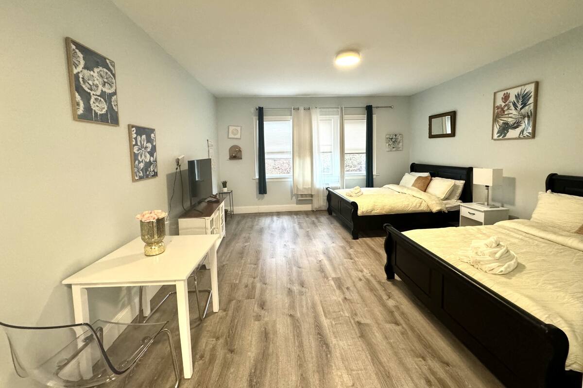 Ein Schlafzimmer mit zwei Betten, einem Schreibtisch, einem Fernseher und Bildern an den Wänden.