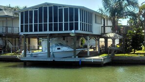 A houseboat with a covered deck and a boat docked underneath. - Fisherman's Paradise-Closest Canal Rental to Bait,Gas,Restaurant& Bar by Boat (Galveston)