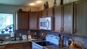 A kitchen with wooden cabinets, a microwave, a stove, and various kitchen appliances. - Fisherman's Paradise-Closest Canal Rental to Bait,Gas,Restaurant& Bar by Boat (Galveston)