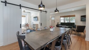 Un amplio comedor con una larga mesa de madera, sillas modernas e iluminación colgante.