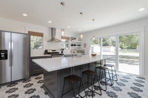 Una cocina moderna con una isla grande, electrodomésticos de acero inoxidable y taburetes de bar.