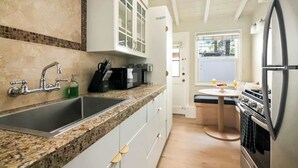 Una cocina moderna con encimeras de granito, electrodomésticos de acero inoxidable y un pequeño comedor con vistas.