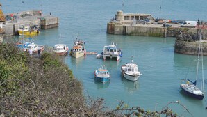 Un port où sont amarrés divers bateaux, une jetée en pierre et des bâtiments en arrière-plan.