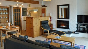 Un salon comprenant un canapé, des fauteuils, une table basse, une cheminée et un téléviseur.