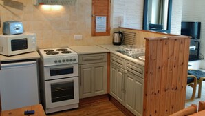 Une cuisine compacte équipée d’un four à micro-ondes, d’une cuisinière, d’un four et d’un meuble en bois.