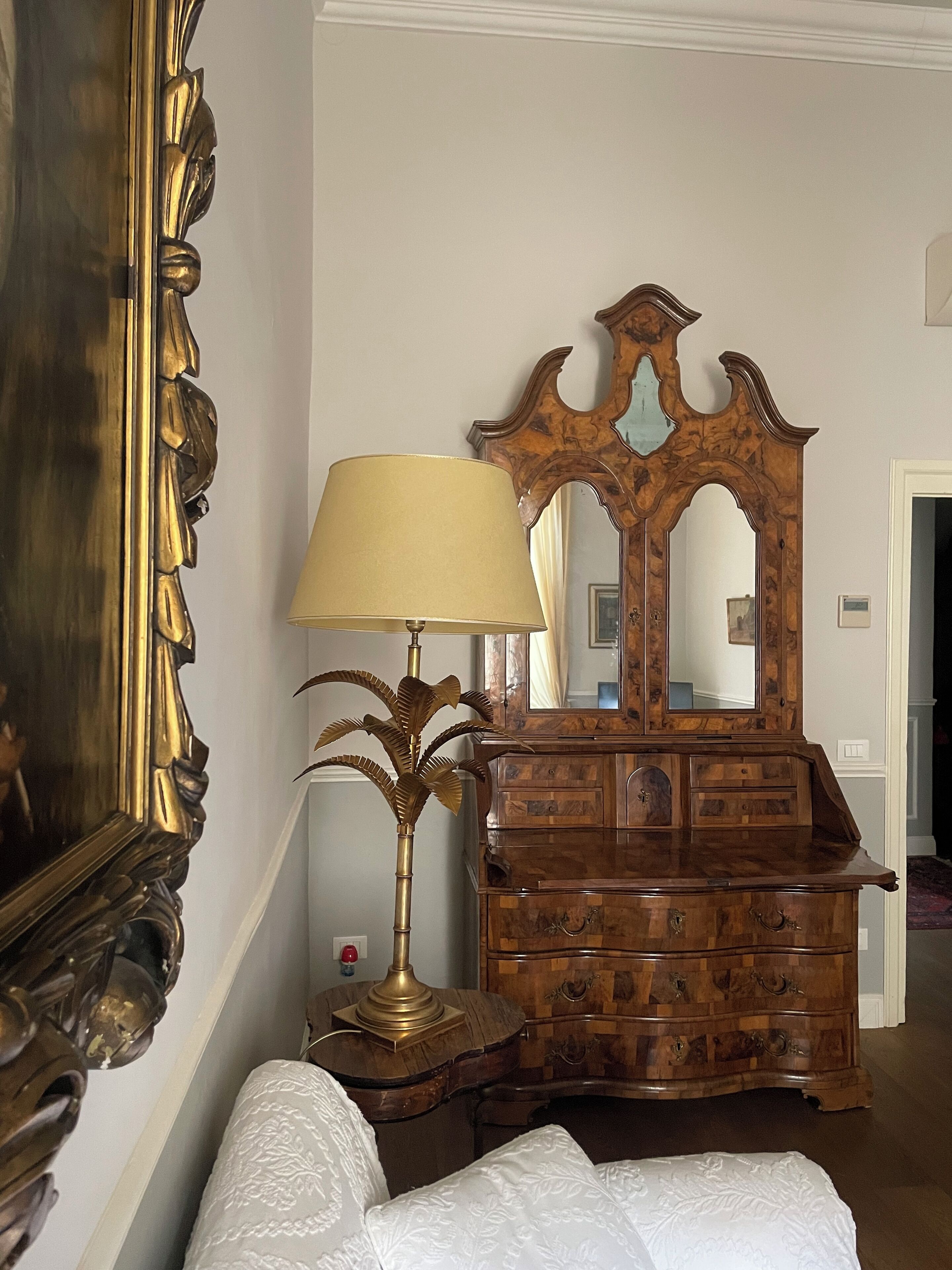 A bedroom with a wooden dresser, a mirror, a lamp, and a bed.