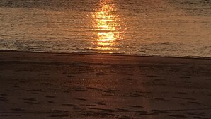 Um pôr do sol sobre águas calmas, com uma linha de costa distante.