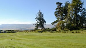 A grassy field with trees and distant mountains. - 2 bedroom accommodation in Auchterarder (Auchterarder)