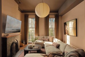 Una sala de estar con chimenea, un sofá, una mesa de centro y un cuadro grande en la pared.