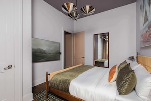 A bedroom with a bed, a painting, a mirror, and a door.