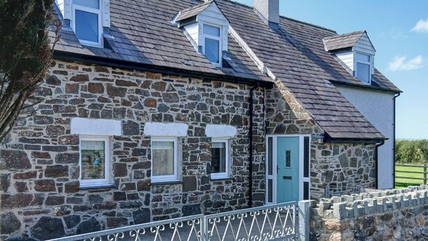 A stone house with a metal gate, a door, and multiple windows.