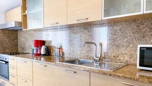 Una cocina moderna con encimeras de granito, electrodomésticos de acero inoxidable y armarios de madera.