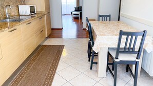 Una cocina moderna con microondas, pileta y muebles de madera. Hay un comedor con una mesa y sillas.