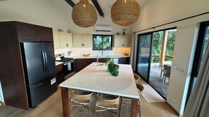 A modern kitchen with dark cabinetry, a central island, and two hanging wicker pendant lights. - Spectacular 270 degree ocean/mountain VIEWS, very private, recently remodeled (Nosara)