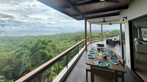 A dining area with a table set for four, overlooking a lush landscape. - Spectacular 270 degree ocean/mountain VIEWS, very private, recently remodeled (Nosara)