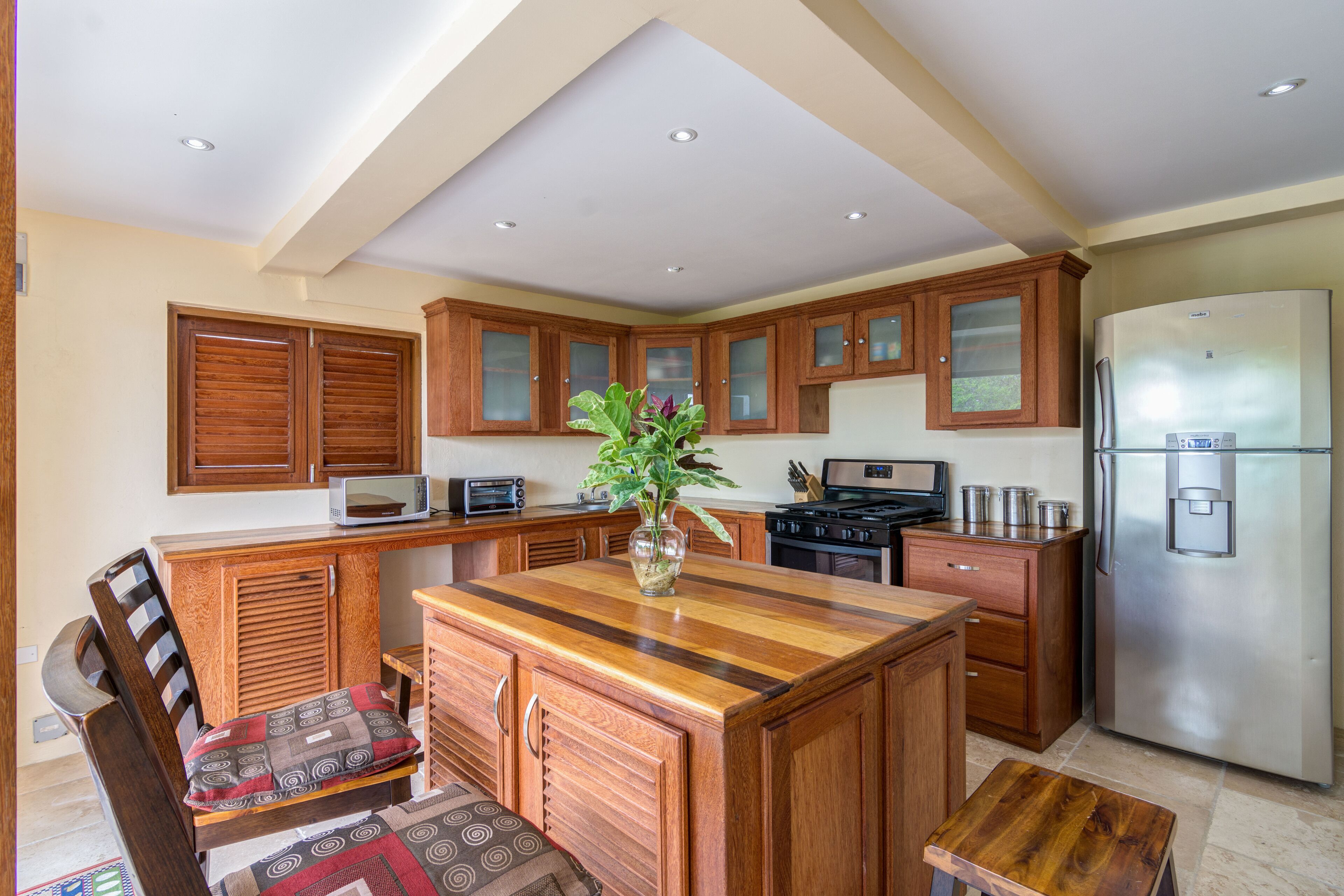 A kitchen with wooden cabinets, a central island, a refrigerator, and a microwave.