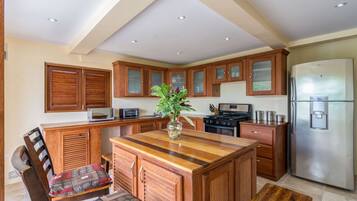A kitchen with wooden cabinets, a central island, a refrigerator, and a microwave.