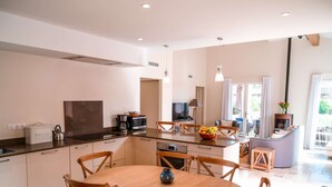 A modern kitchen with a central island, wooden chairs, and a dining table.