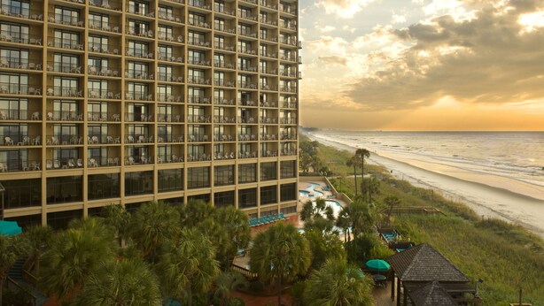 Un hôtel de grande hauteur doté de nombreux balcons donnant sur une plage.