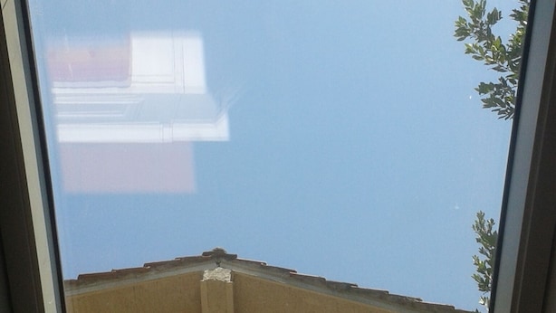 A skylight window with a view of a building's roof and a tree. - Oasis in ROME NORTH (Roma)