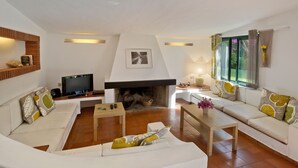 Ein Wohnzimmer mit Kamin, zwei Sofas, einem Fernseher und einem Esstisch.