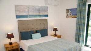 Ein Schlafzimmer mit einem großen Bett, zwei Nachttischen, einer Kopfteil und Kunstwerken an den Wänden.