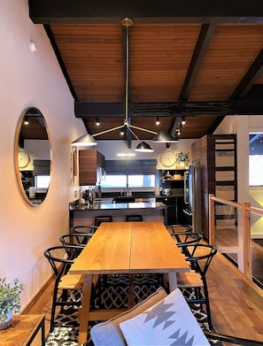 A modern kitchen with a central island, wooden ceiling beams, and pendant lighting.