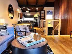 A modern living room with a sofa, a coffee table, and a dining area with a wooden table and chairs. - Walk to Canyon Lodge Lifts!! 2BR/2BA Condo w/ BBQ (Mammoth Lakes)