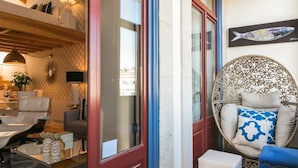 A modern living room with a dining area, a large window, and a decorative fish painting. - Oporto Golden Apartment - your luxury choice in the Heart of Porto (Porto)