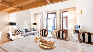A spacious living area with a marble dining table, wooden ceiling beams, and a sofa with patterned cushions. - Oporto Golden Apartment - your luxury choice in the Heart of Porto (Porto)