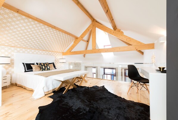 Ein Schlafzimmer mit hohen Decken, einem Bett, einem Nachttisch und einem schwarzen Teppich.
