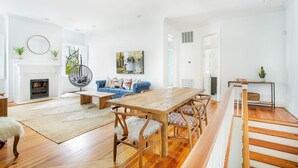 A spacious living room with a wooden dining table, blue sofa, and a fireplace.