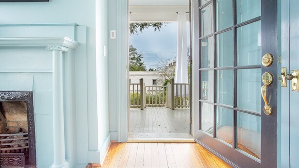 A doorway leading to a wooden deck with a view of a house and trees.