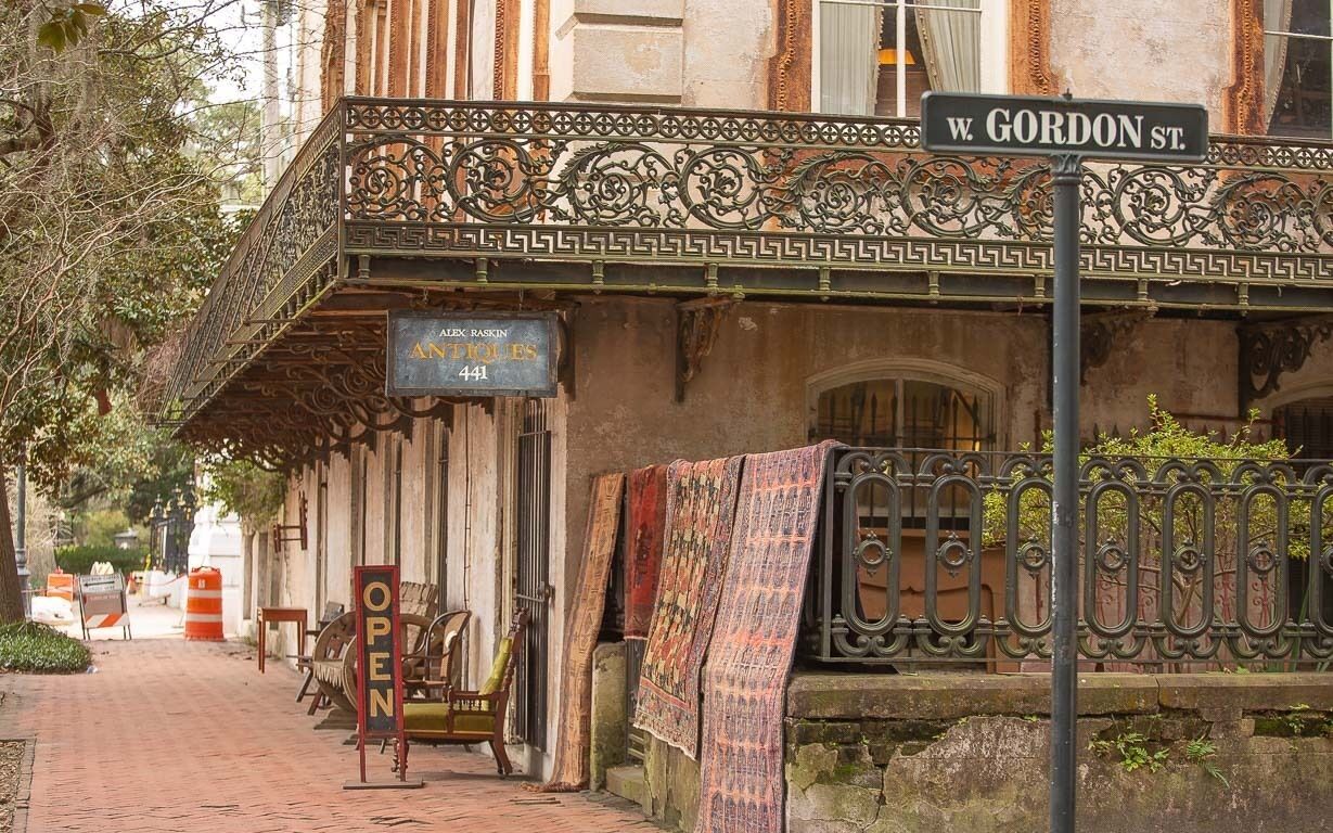 Een gebouw met een balkon van ijzerwerk en een straatnaambord voor W. Gordon St.