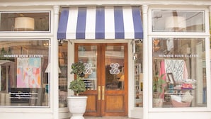 A storefront with a striped awning, large windows displaying furniture, and a sign reading "NUMBER FOUR ELEVEN".
