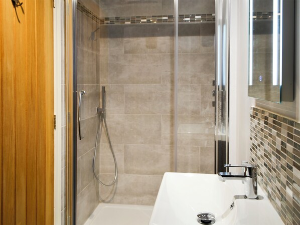 A bathroom with a shower, a sink, and a mirror.