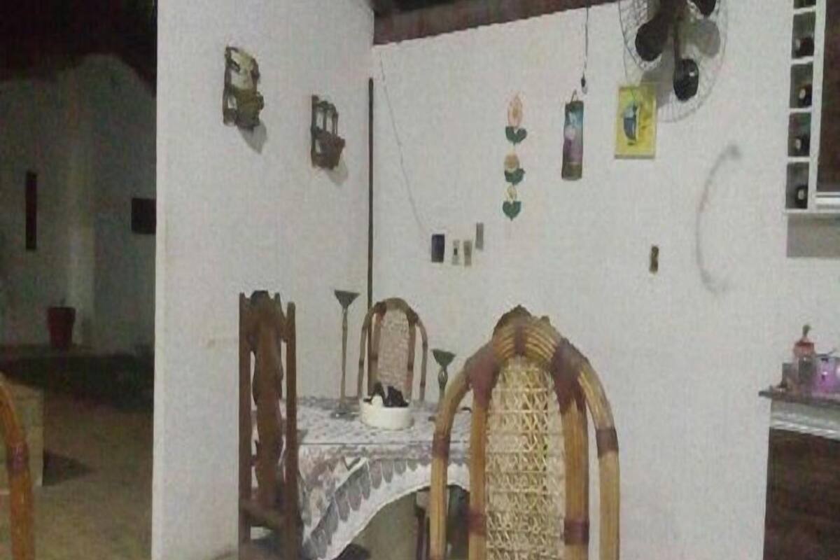 A dining area with a table set for two, a chair, and a small table with a bowl and spoon.