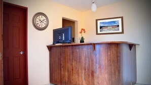 Un mostrador de recepción de madera con un reloj y un cuadro en la pared.