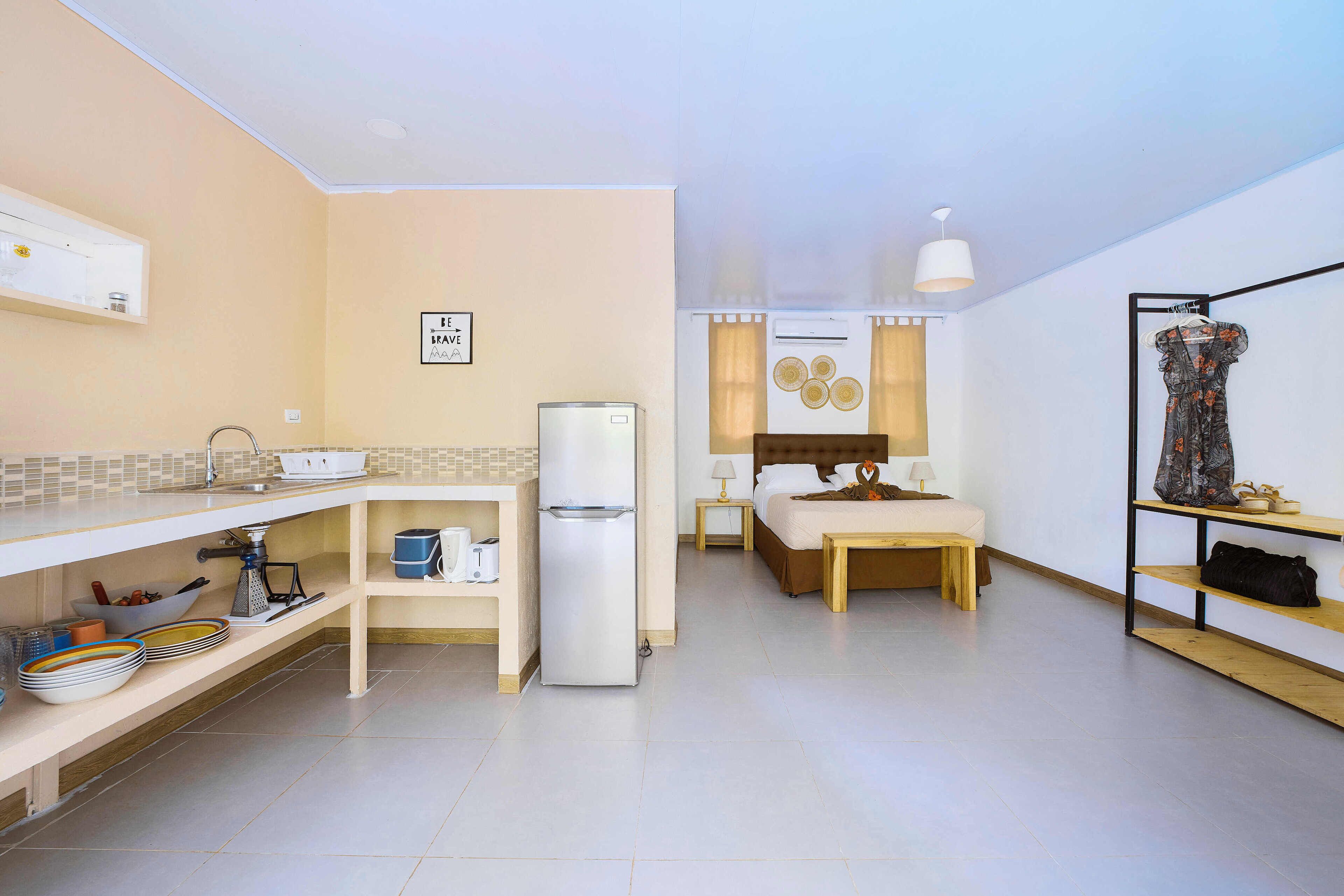 Habitació d'hotel compacte amb cuineta, un llit, una petita zona de menjador i un armari.