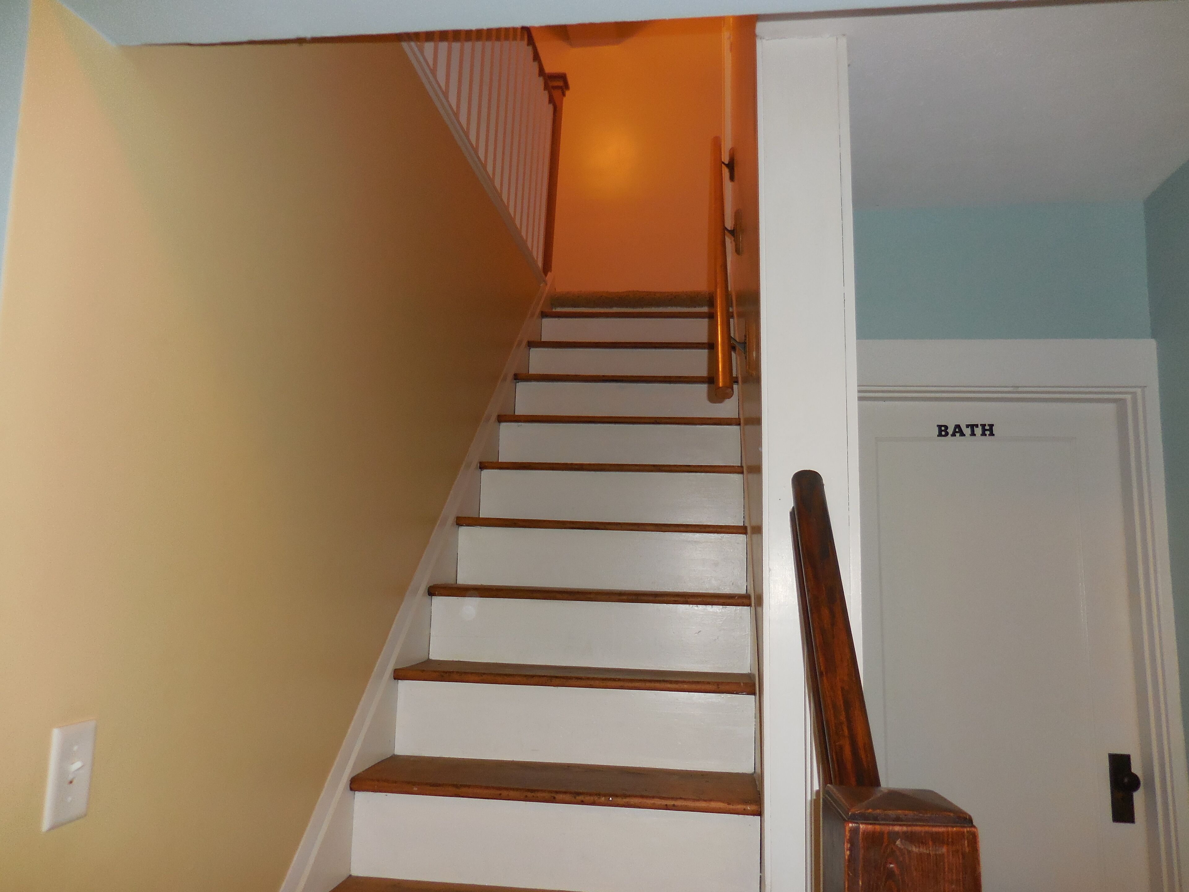 Un escalier avec des marches en bois menant à une porte blanche portant l’inscription « SALLE DE BAIN ».