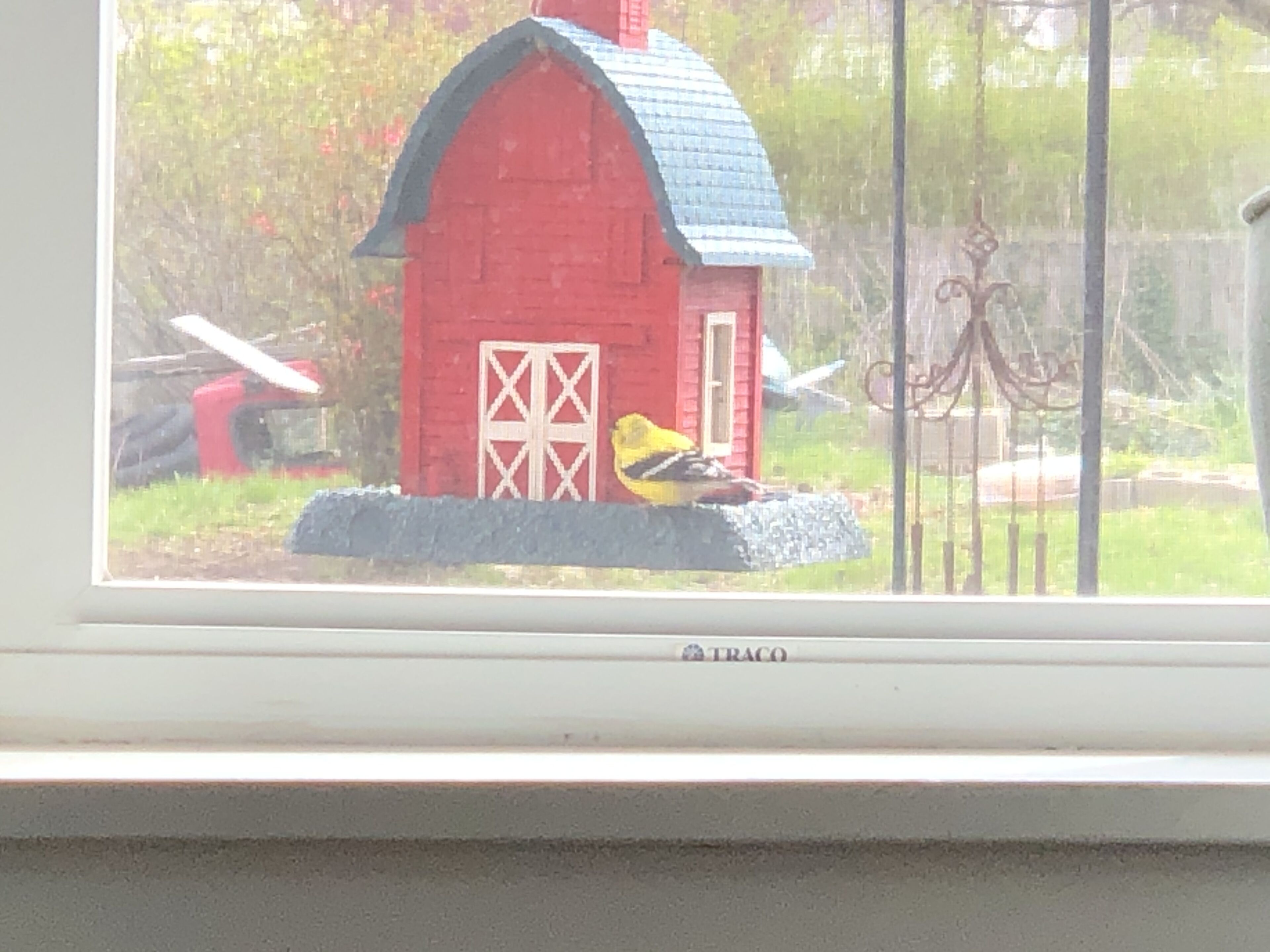 A red barn with a yellow bird on the roof.